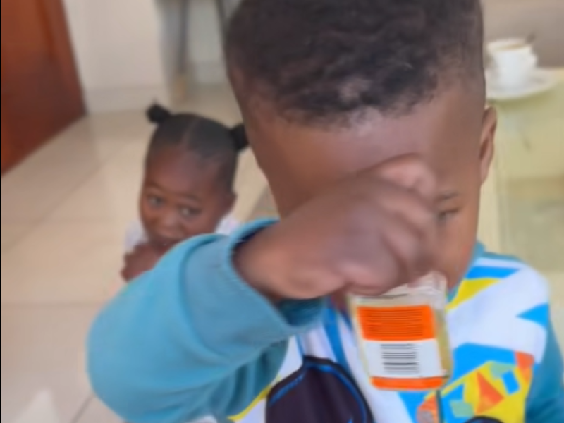 A toddler holds a bottle of Castor Oil close to his face