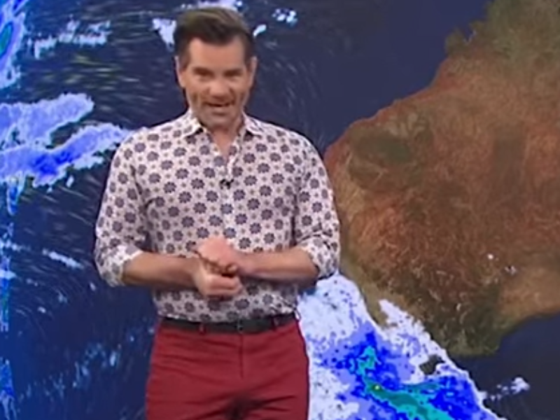 A weather man stands in front of a map