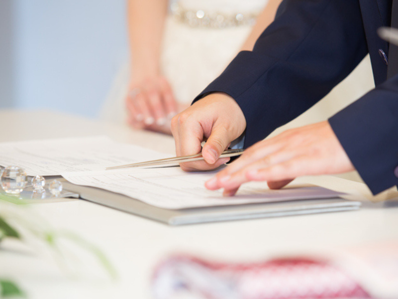 A wedded couple sign documents at their wedding
