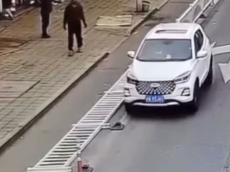 A white van drives over parking barrier on the side of the road