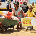 A woman and child transport food on a wheelbarrow during 2024 ECR Season of Sharing