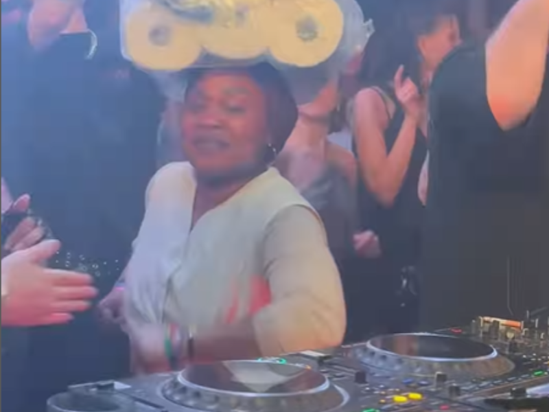 A woman balances a bag of toilet paper on her head while dancing at a club