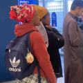 A woman carries a chicken in her backpack outside a bank