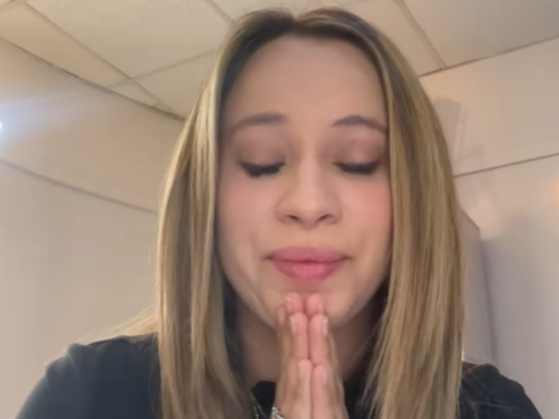 A woman closes her eyes and holds her palms together to say thank you