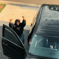 A woman dancing at her car parked in the driveway