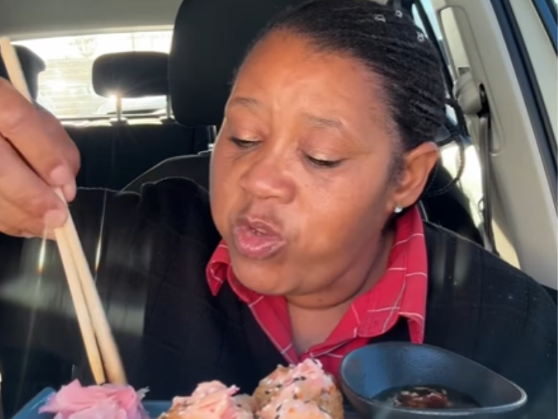 A woman eating sushi inside a car