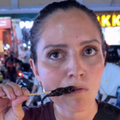 A woman eats a scorpion on the streets of Bangkok
