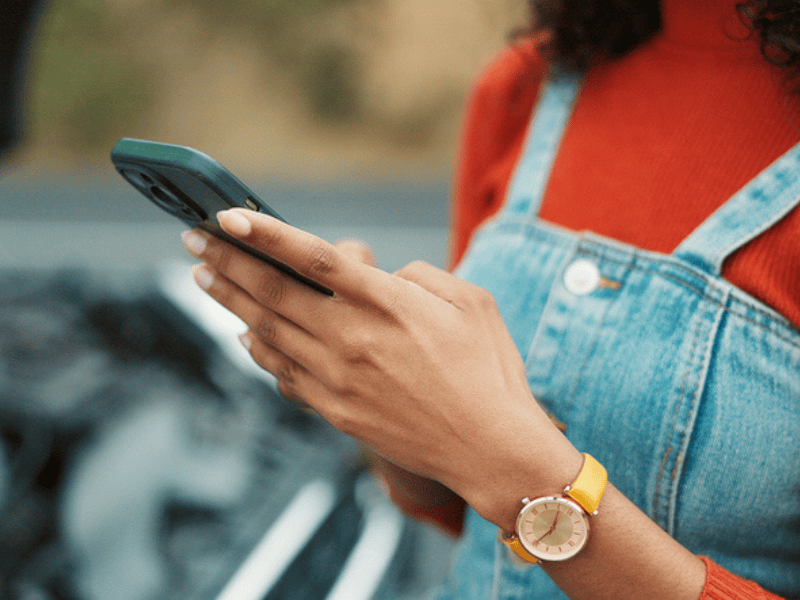 A woman holding her phone waiting for roadside assistance