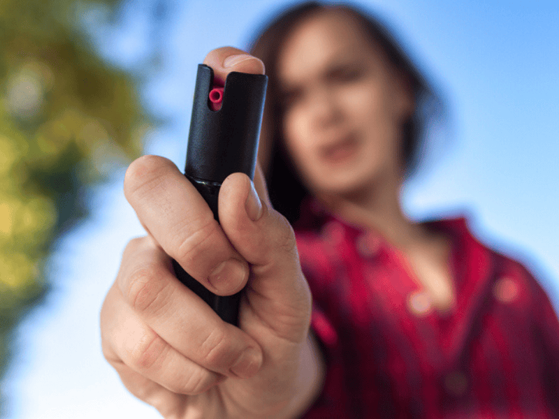 A woman holds a can of pepper spray in defense