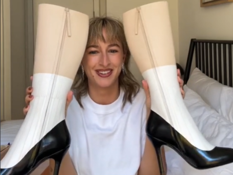 A woman holds boots that look like fake legs with socks and pumps