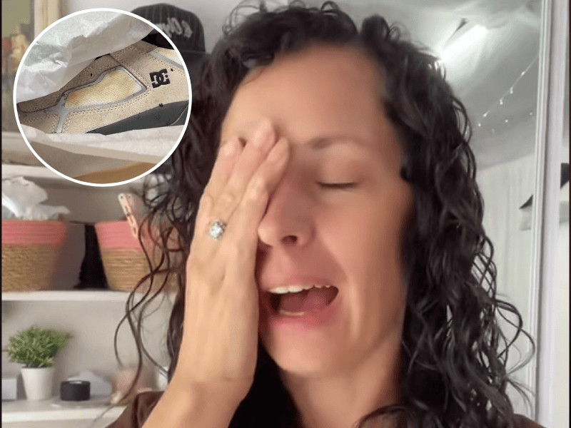 A woman holds her face in despair over a new pair of sneakers that have stains on them