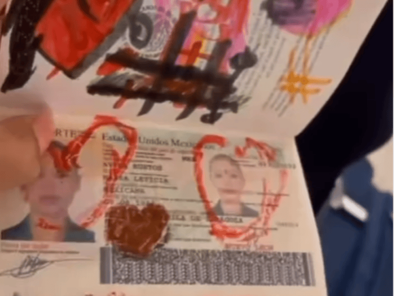 A woman holds open her passport that has her childrens drawings inside