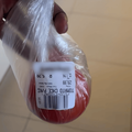 A woman holds up a plastic packet with a tomato inside that has been weighed