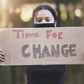 A woman holds up a sign for change in protest
