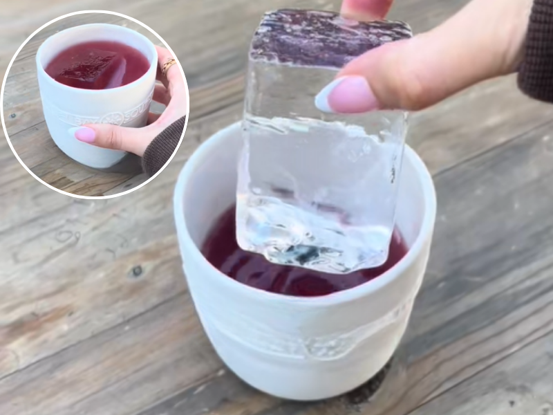 A woman lifts up a large ice block from her alcoholic beverage