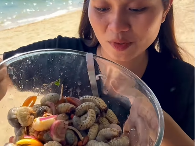 A woman mixes a bowl of coconut worm salad