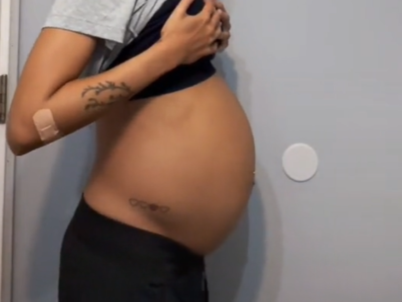 A woman poses in a side profile of her large belly