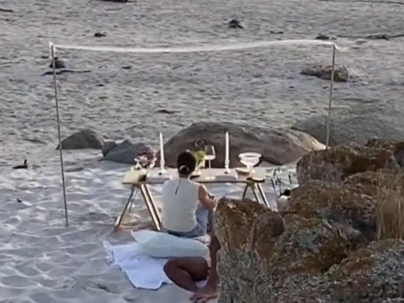 A woman seated at a picnic on the beach