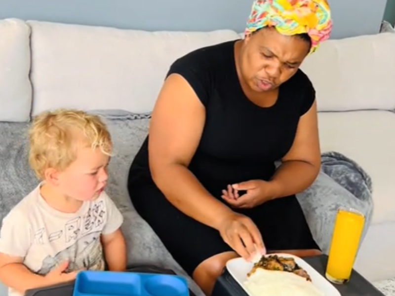 A woman showing a child how to eat pap and vegetables