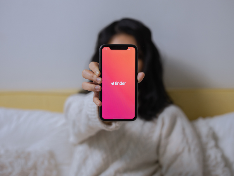 A woman showing her smartphone with Tinder App