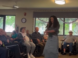 A woman singing for a group of people in the nursing home