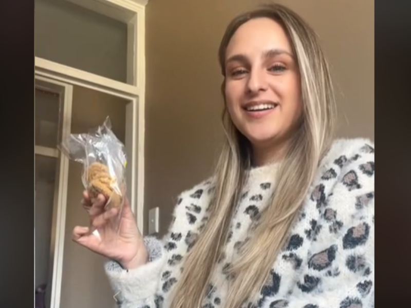 A woman sits on her couch with a packet of Murkoo