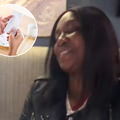 A woman sitting at a restaurant smiling hands looking at restaurant bill