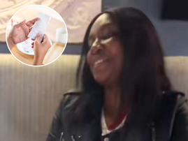 A woman sitting at a restaurant smiling hands looking at restaurant bill