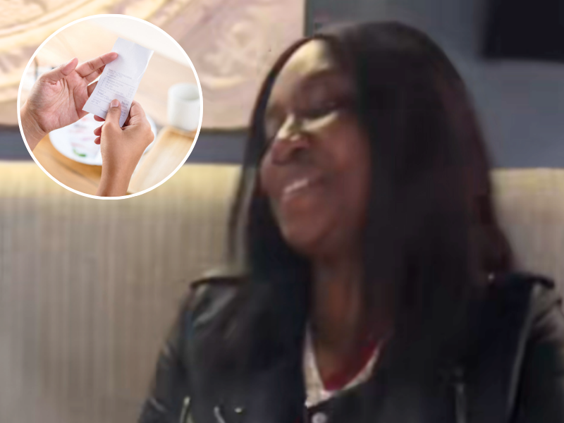 A woman sitting at a restaurant smiling hands looking at restaurant bill