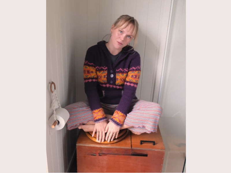 A woman sitting on a compost toilet