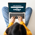 A woman sitting on the floor using her laptop to search for a job