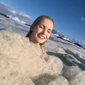 A woman swimming amongst the sea foam at Cape Town beach