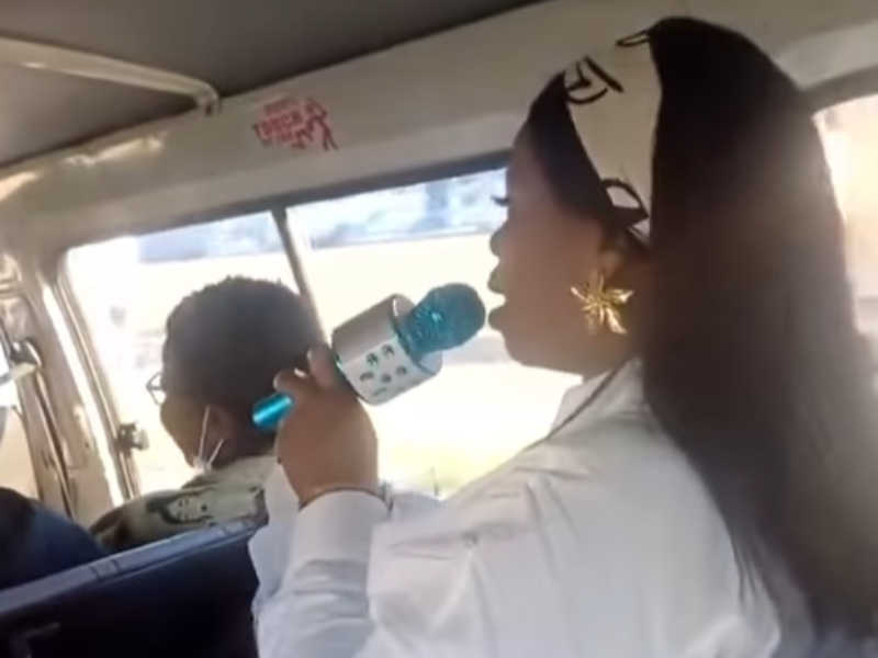 A woman traveling in a taxi uses a microphone