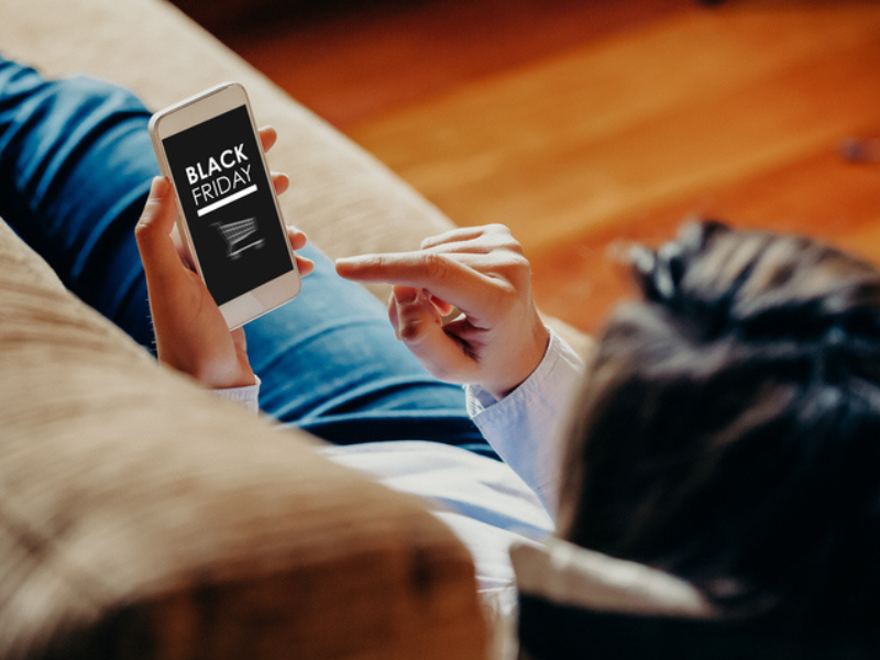 A woman using a mobile phone to shop for Black Friday