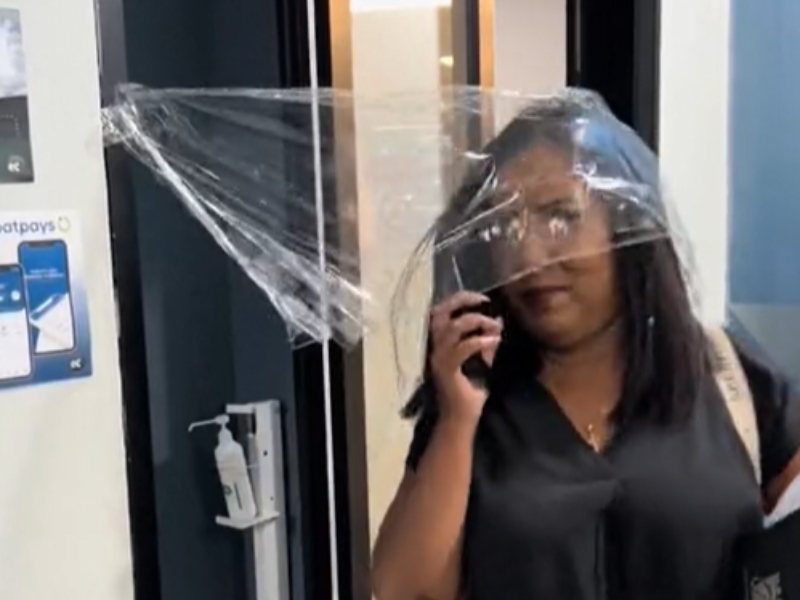 A woman walks through cling wrapped door frame at the office