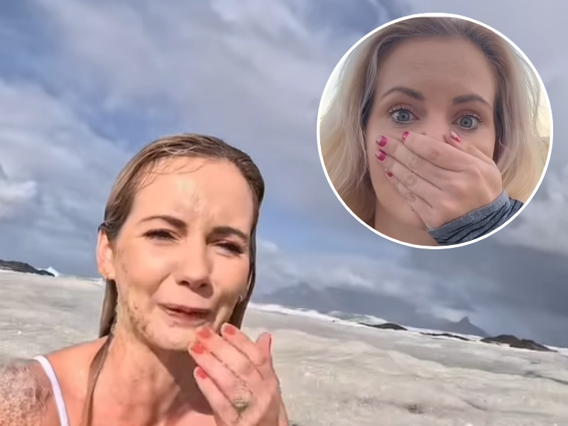 A woman wearing a bikini wiping her mouth after swallowing some sea water
