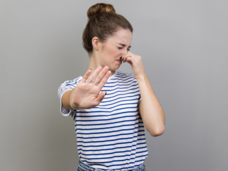 A woman with a bun hairstyle blocking her nose from a bad smell