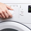 A woman's hand launches a white washing machine