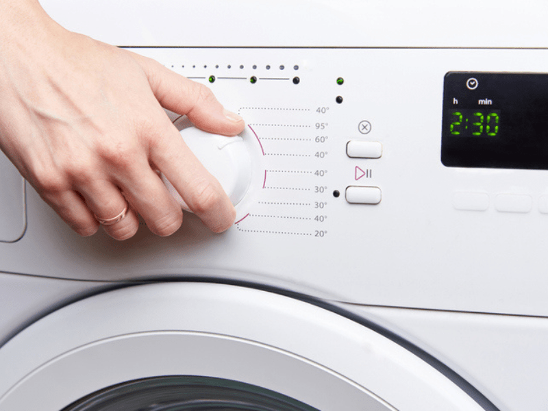 A woman's hand launches a white washing machine