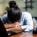 A worker puts her head down on her laptop burned out