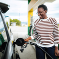 A young adult woman refueling her car at a petrol station