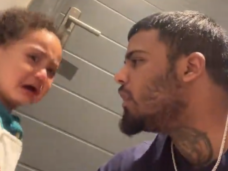 A young baby boy crying while his father tries to comfort him