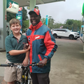 A young boy stands with a Caltex petrol attendant gifting him a bicycle