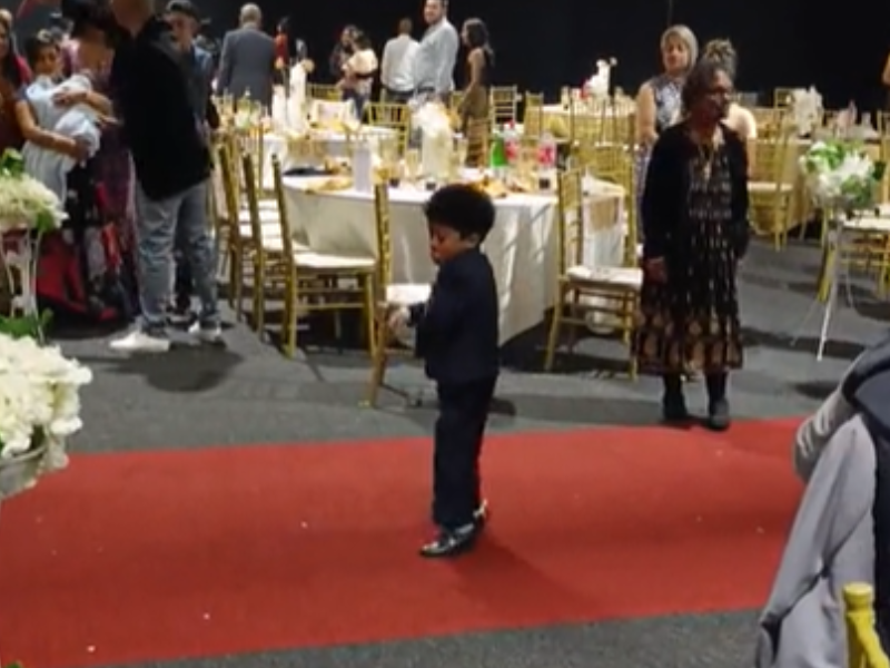 A young boy wearing a suit dancing at a function