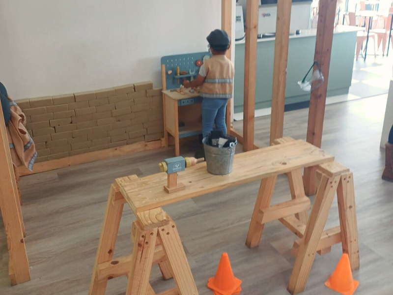 A young child playing at a woodwork role play area