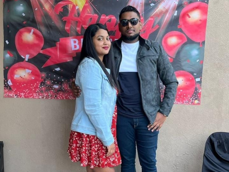 A young couple from KZN stand in front of a birthday sign