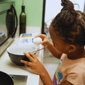 A young girl cracks an egg into a bowl