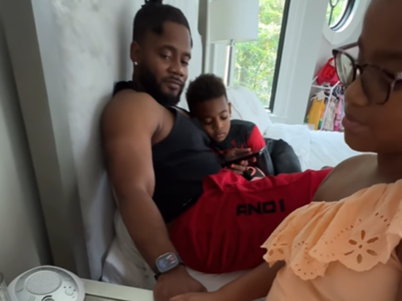 A young girl does her father's nails while he sits on the bed
