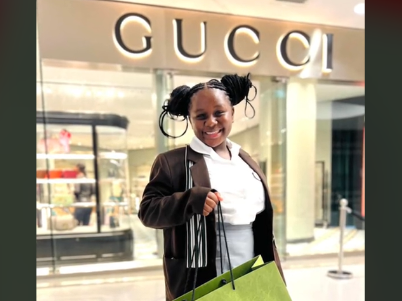 A young girl standing in front of Gucci store