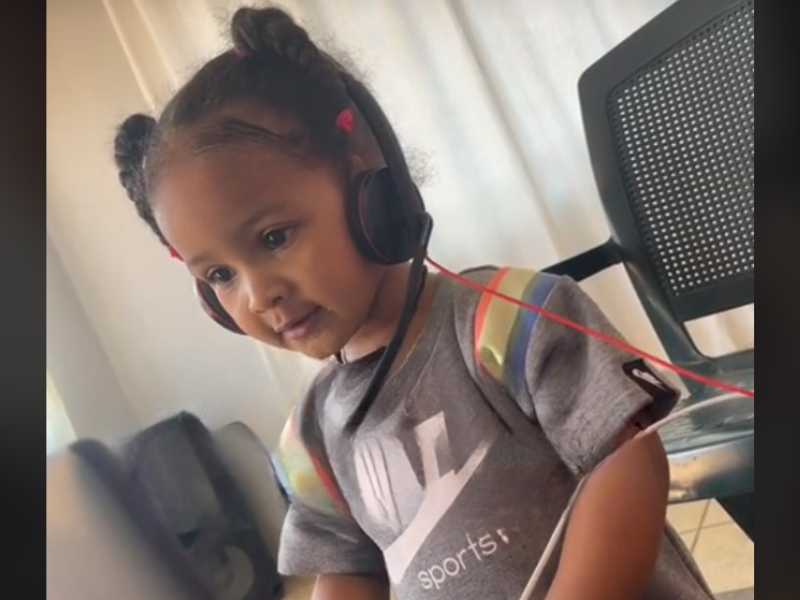 A young girl using a headset and working on a laptop